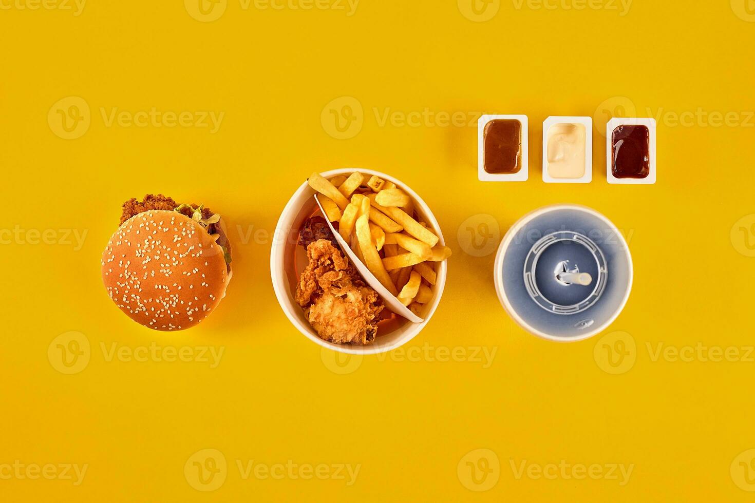 Fast food dish top view. Meat burger, potato chips and wedges. Take away composition. French fries, hamburger, mayonnaise and ketchup sauces on yellow background. photo
