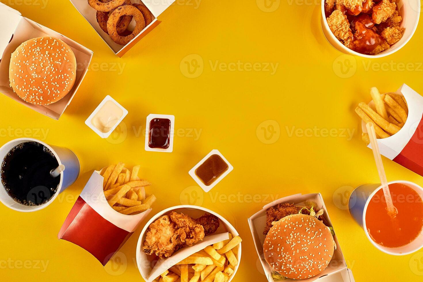Fast food dish top view. Meat burger, potato chips and wedges. Take away composition. French fries, hamburger, mayonnaise and ketchup sauces on yellow background. photo