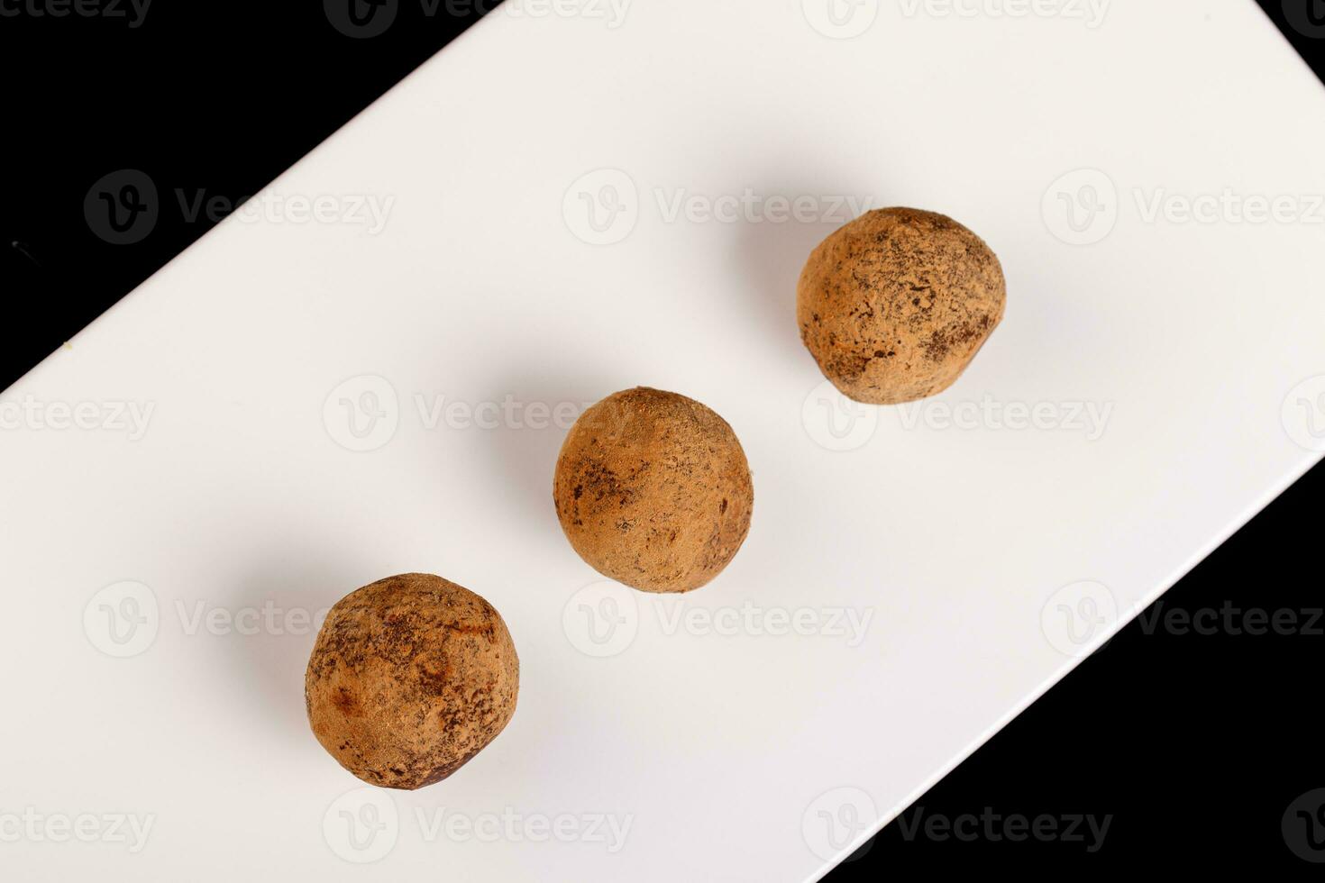 hermosa caramelo trufa en un blanco plato en un negro antecedentes foto