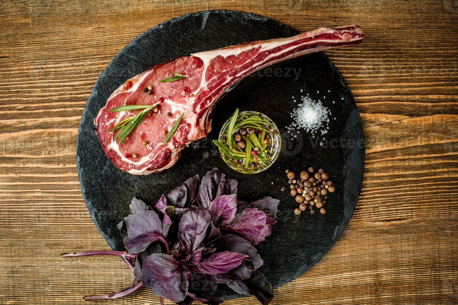 Dry aged raw tomahawk beef steak with ingredients for grilling photo