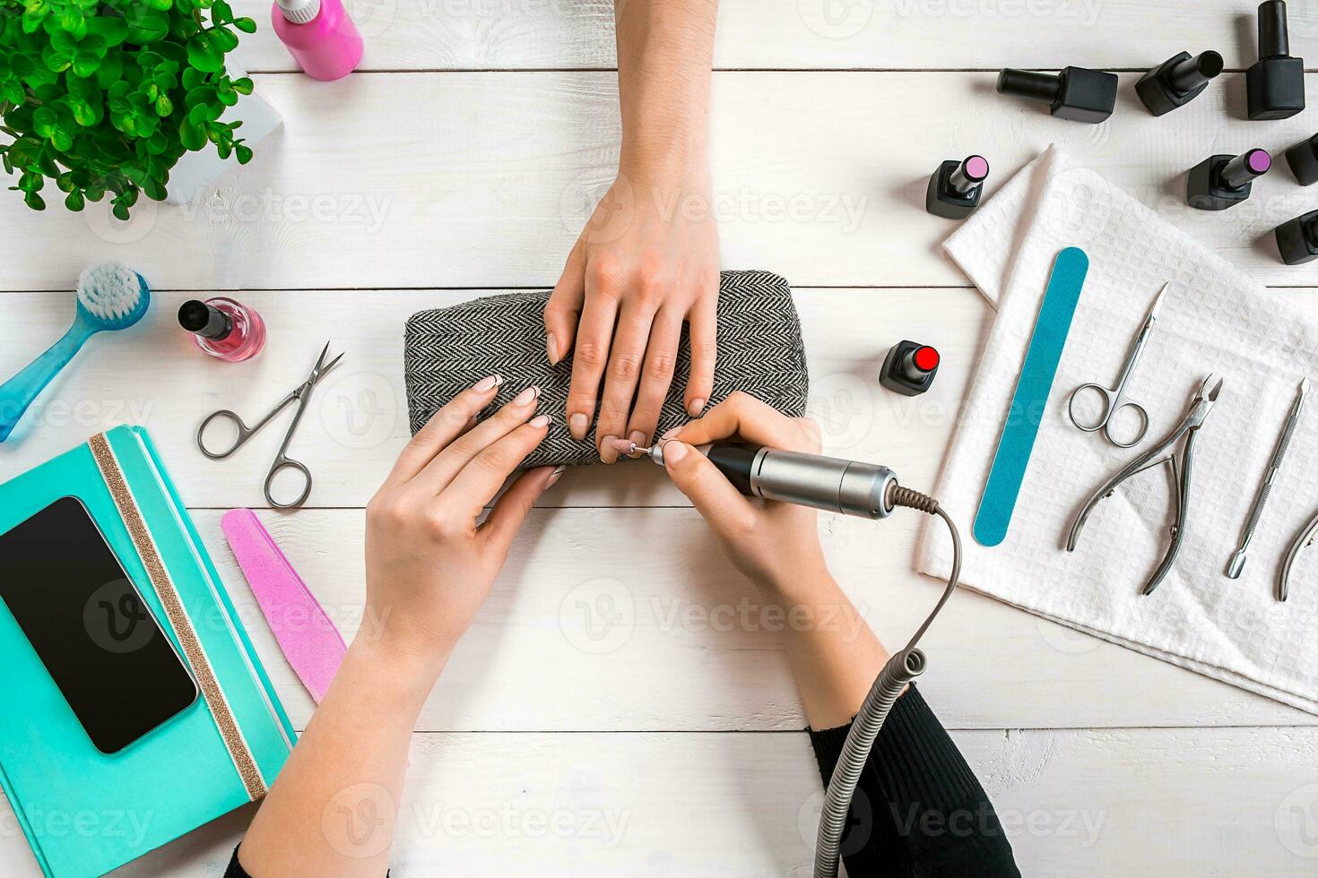 Nail care. Closeup of female hands filing nails with professional nail file in beauty nail salon. Top view photo