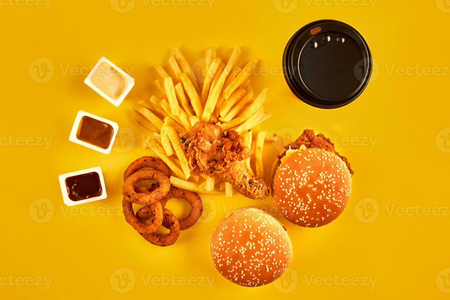 Fast food concept with greasy fried restaurant take out as onion rings, burger, fried chicken and french fries as a symbol of diet temptation resulting in unhealthy nutrition. photo