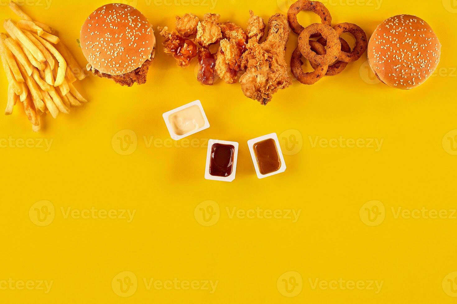 Fast food dish top view. Meat burger, potato chips and wedges. Take away composition. French fries, hamburger, mayonnaise and ketchup sauces on yellow background. photo