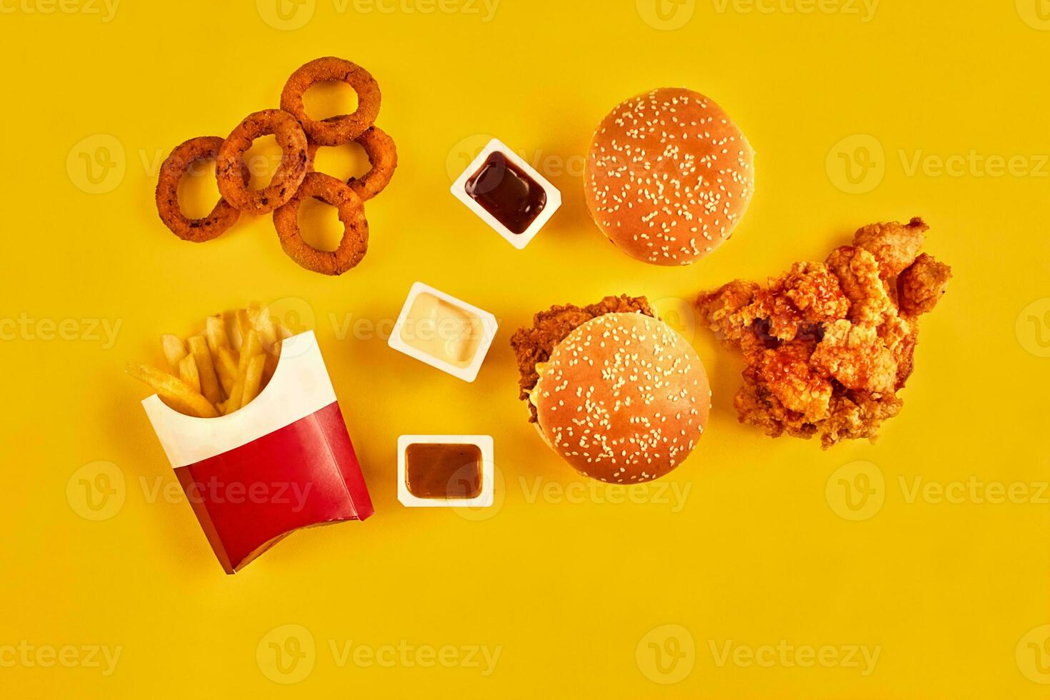 Top view hamburger, french fries and fried chicken on yellow background. Copy space for your text. photo