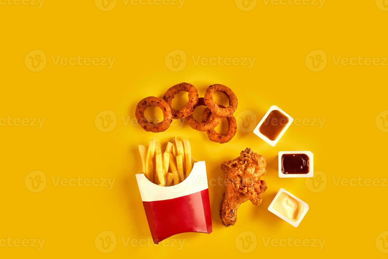 Fast food dish top view. French fries, hamburger, mayonnaise and ketchup sauces on yellow background. photo
