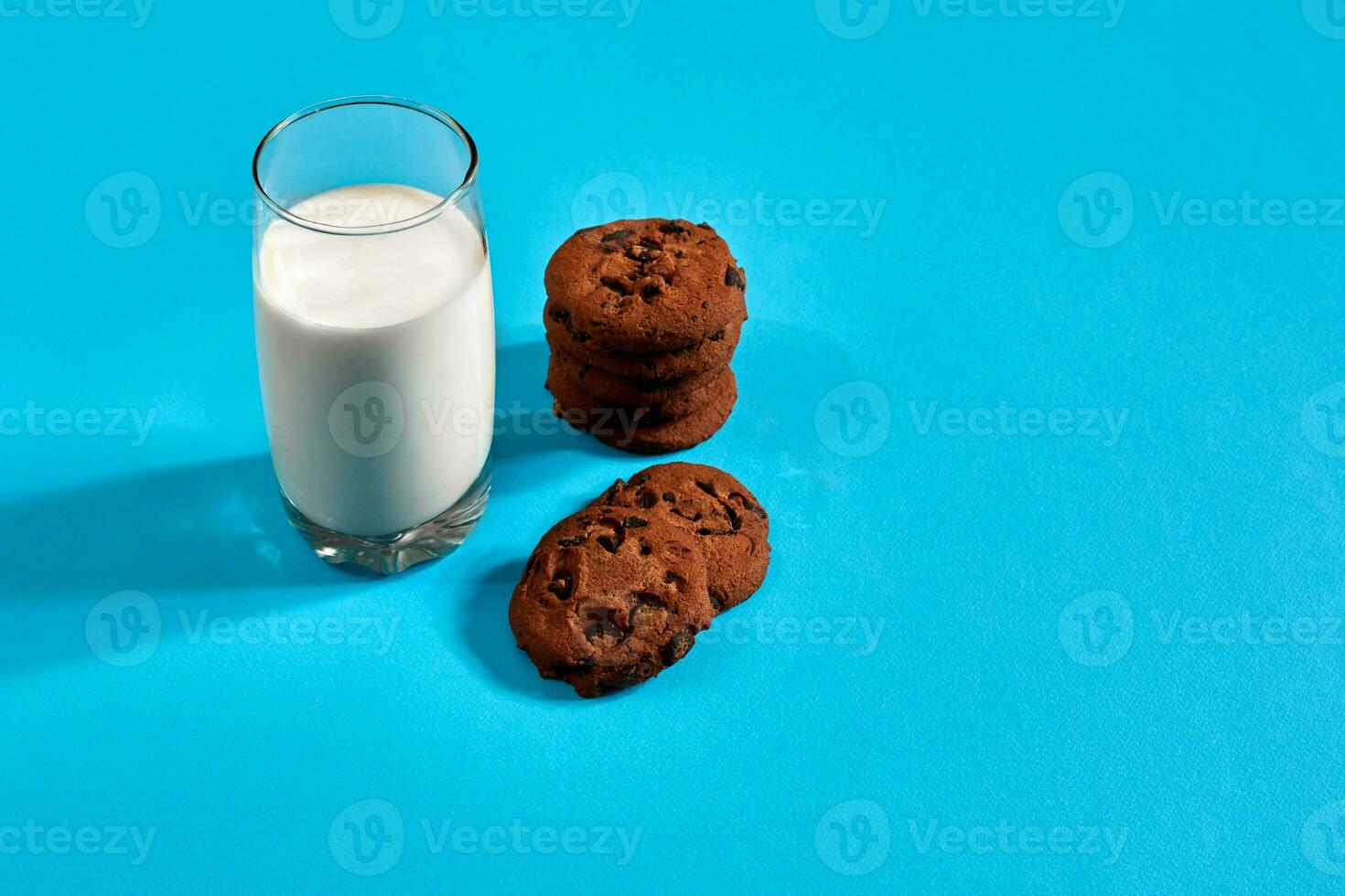 Glass of milk and cookies on blue background with space for text or design photo