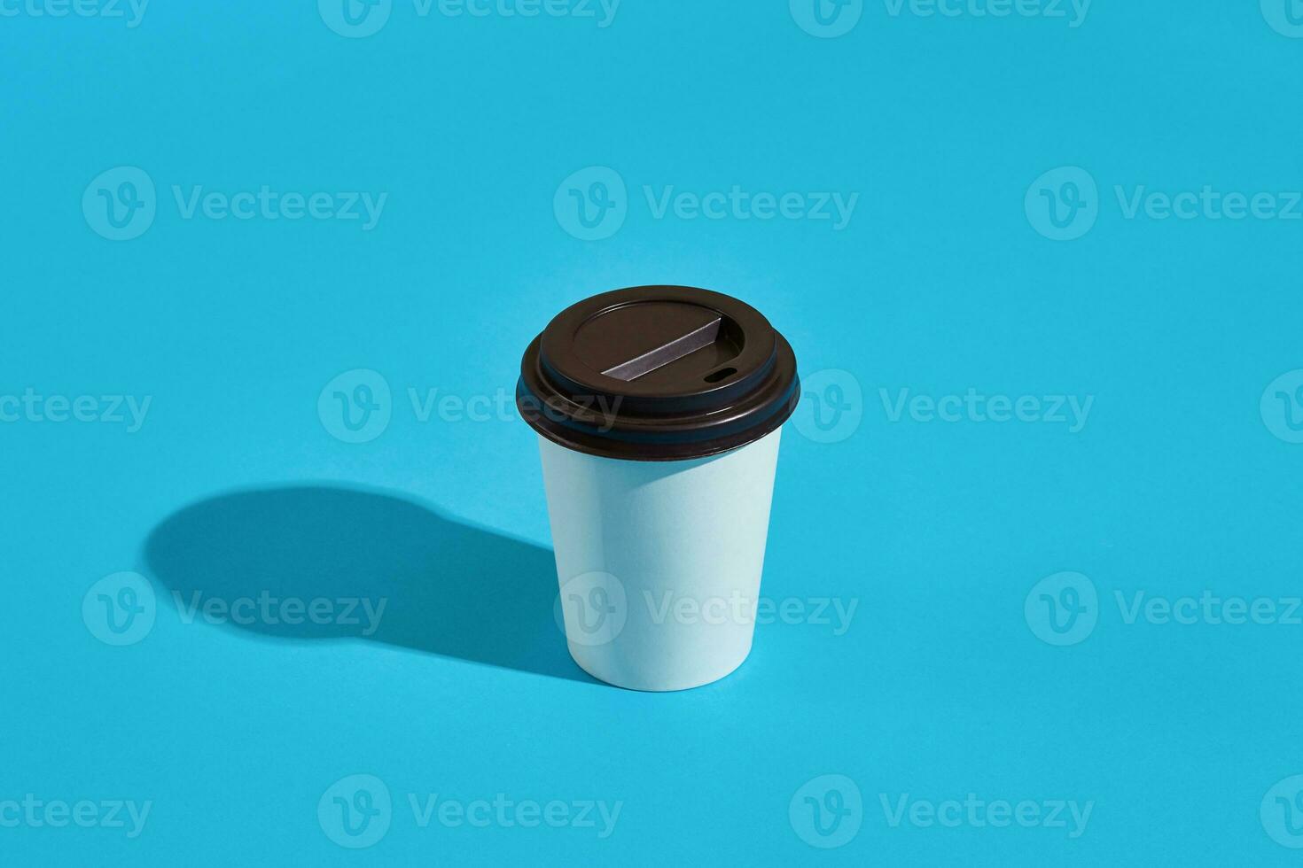 Hot coffee in white paper cup with black lid on blue background photo