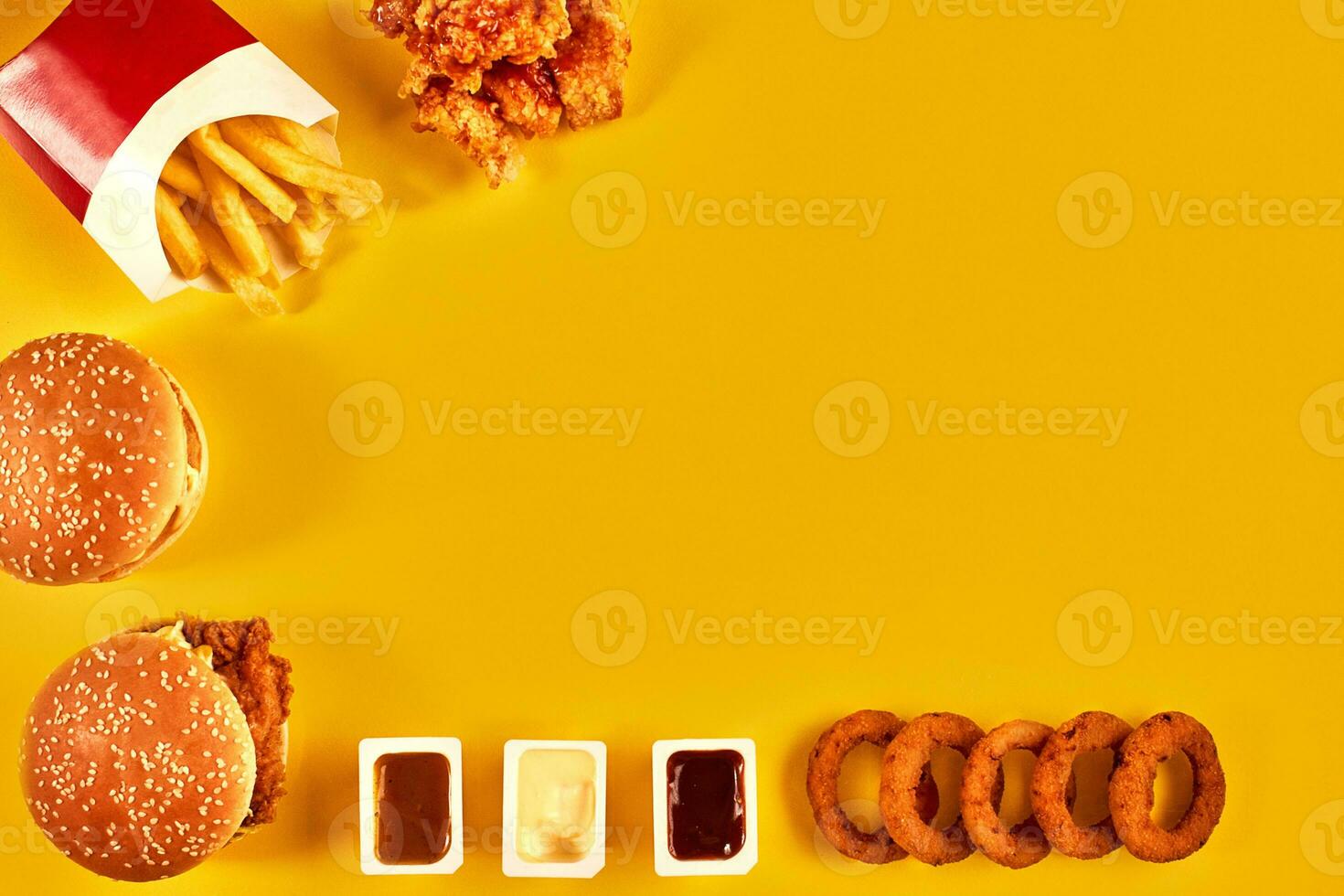 Top view hamburger, french fries and fried chicken on yellow background. Copy space for your text. photo