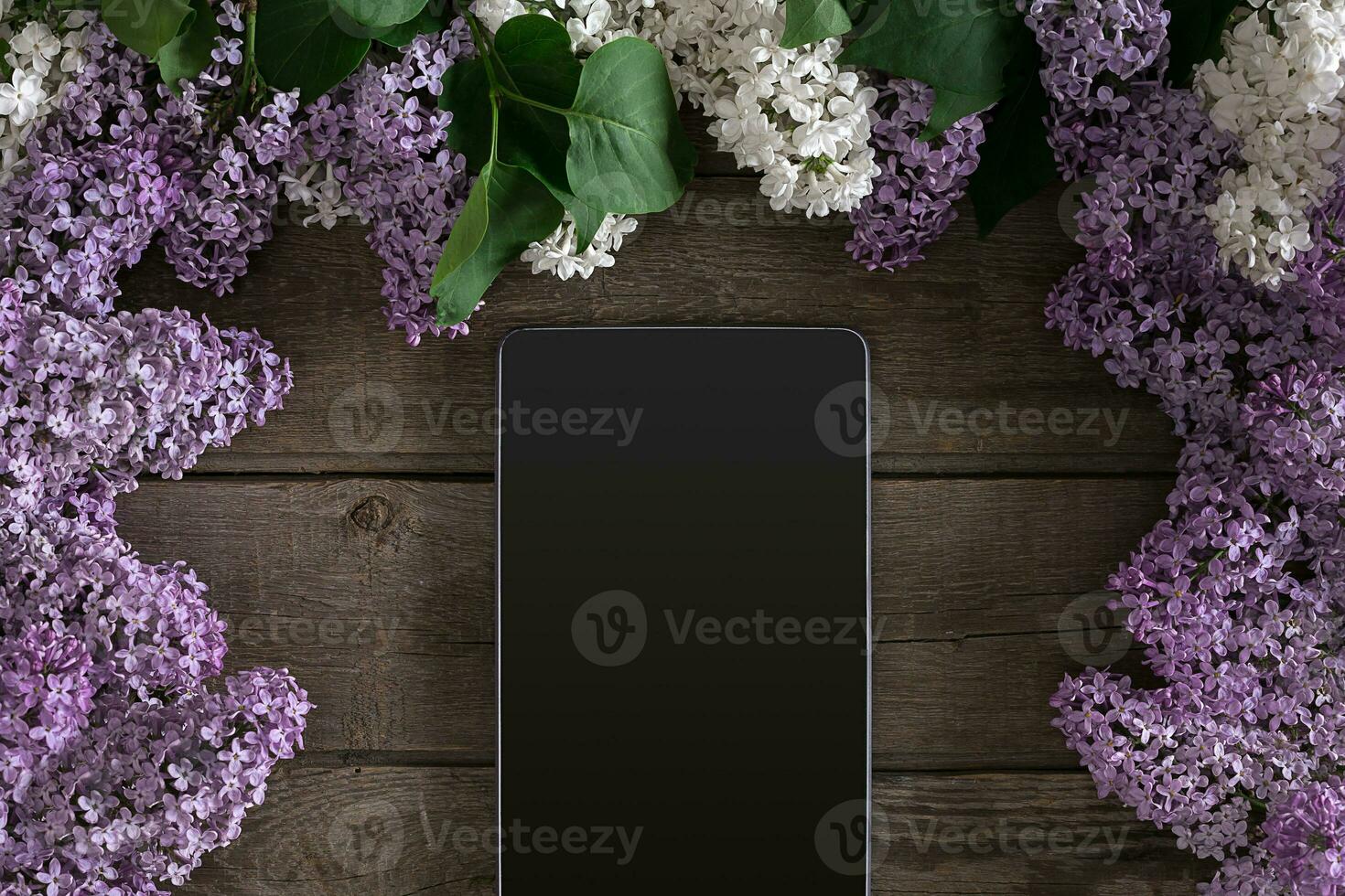 Lilac blossom on rustic wooden background, tablet with empty space for greeting message. Top view photo