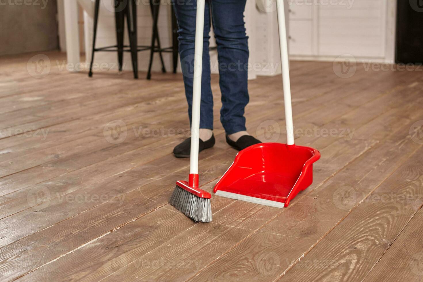 Faceless middle section of young woman sweeping floor on the kitchen photo