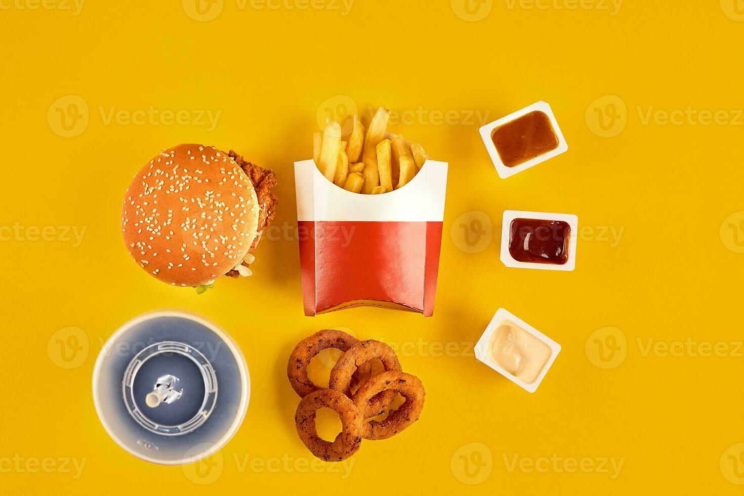 Fast food dish top view. Meat burger, potato chips and wedges. Take away composition. French fries, hamburger, mayonnaise and ketchup sauces on yellow background. photo