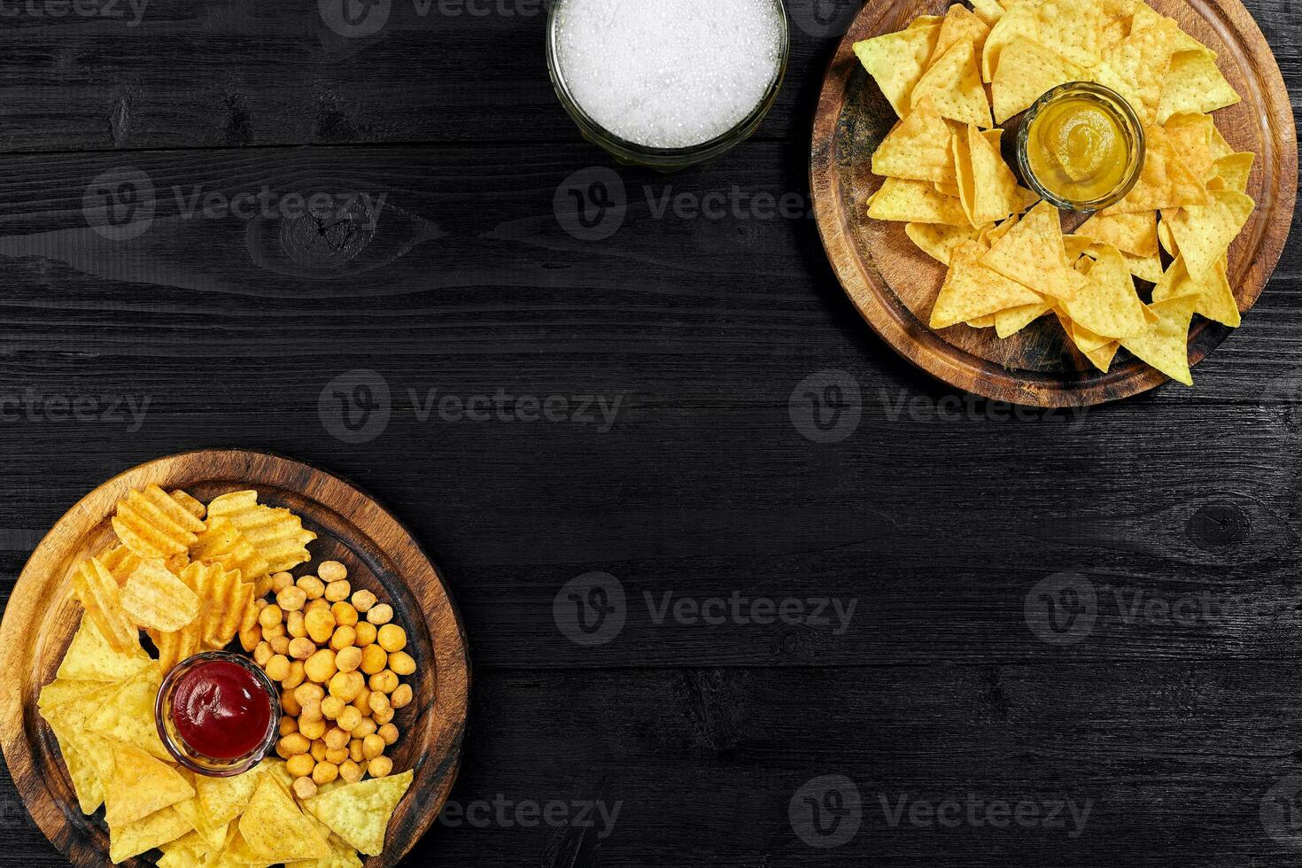 Lager beer and snacks on black wooden table. Nuts, chips. Top view with copyspace photo