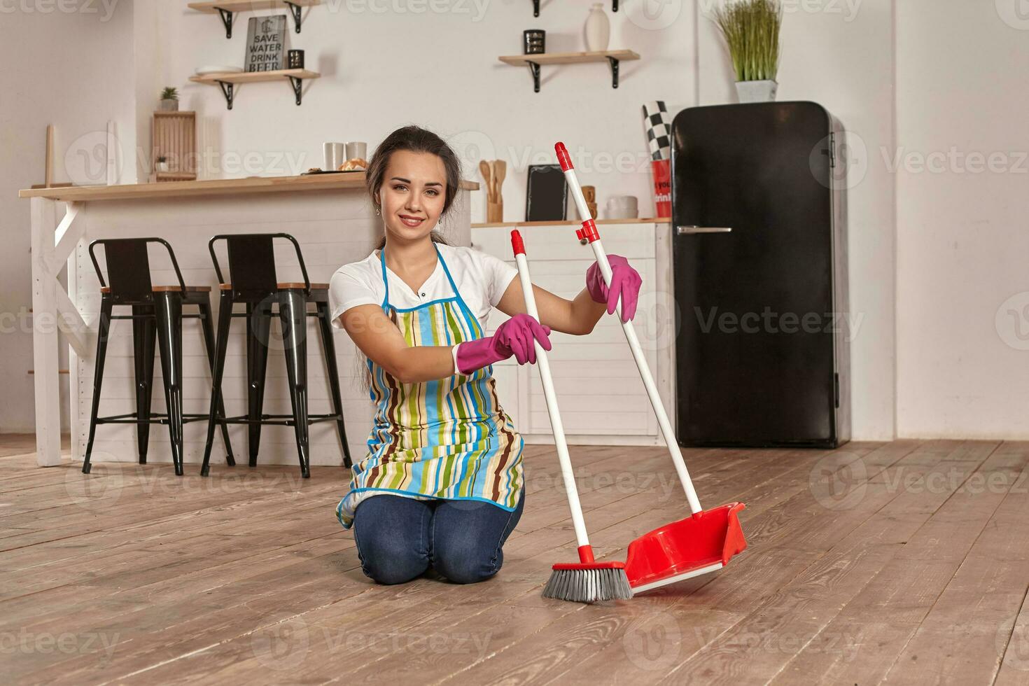 Young woman sweeping floor on the kitchen photo