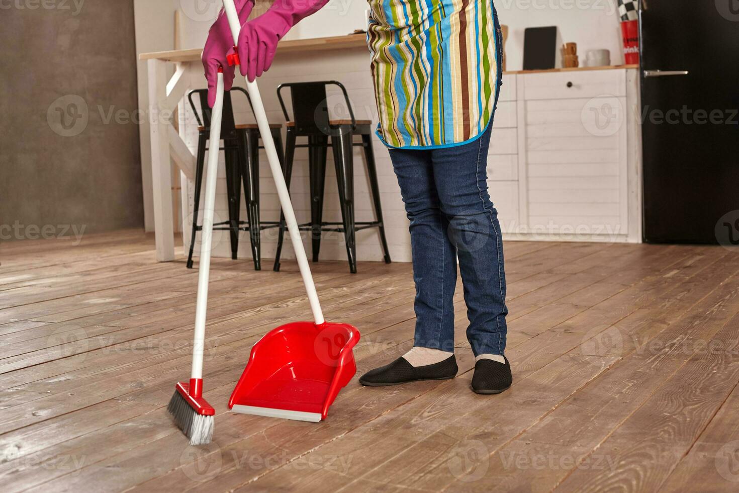 Faceless middle section of young woman sweeping floor on the kitchen photo