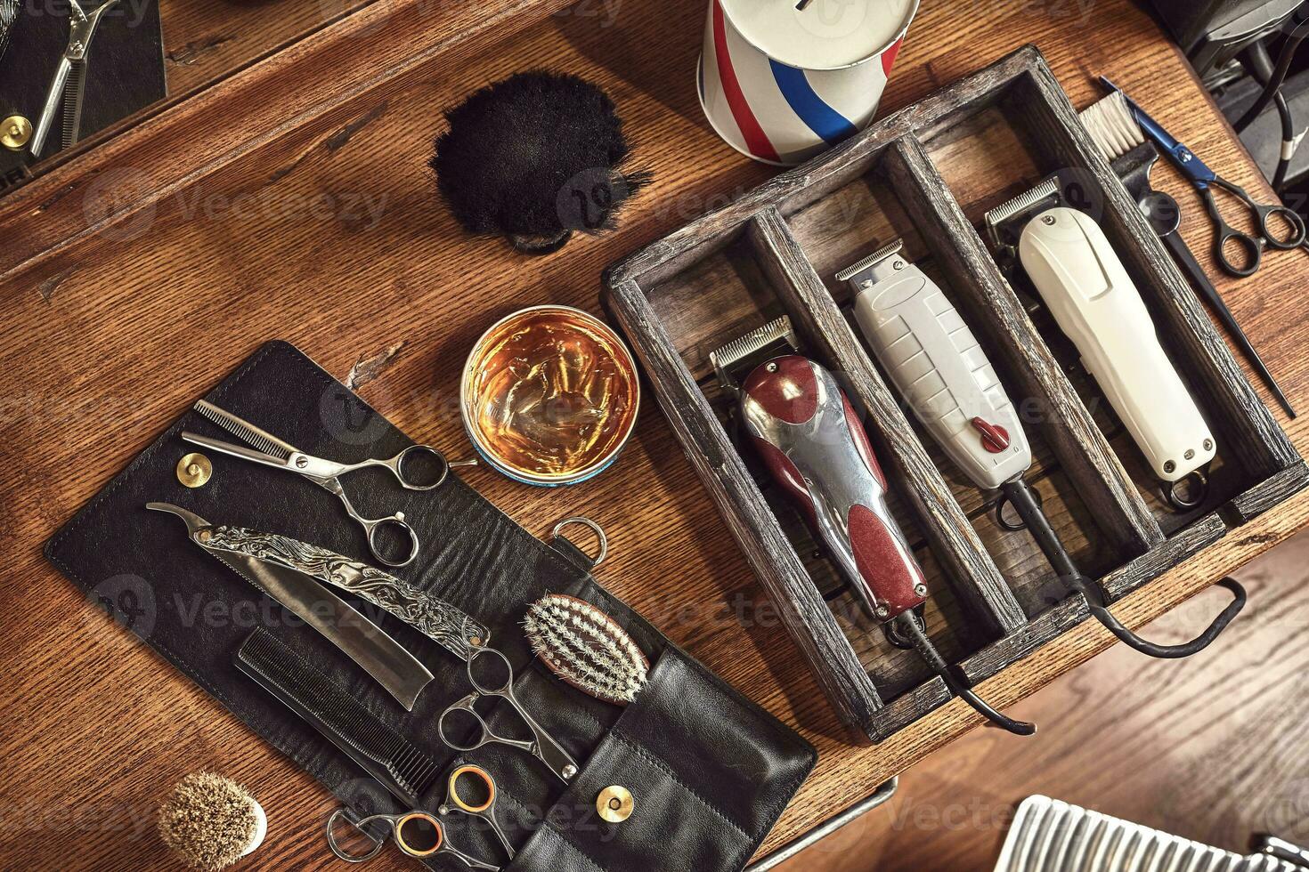 Hairdresser tools on wooden background. Top view on wooden table with scissors, comb, hairbrushes and hairclips, trimmer. photo