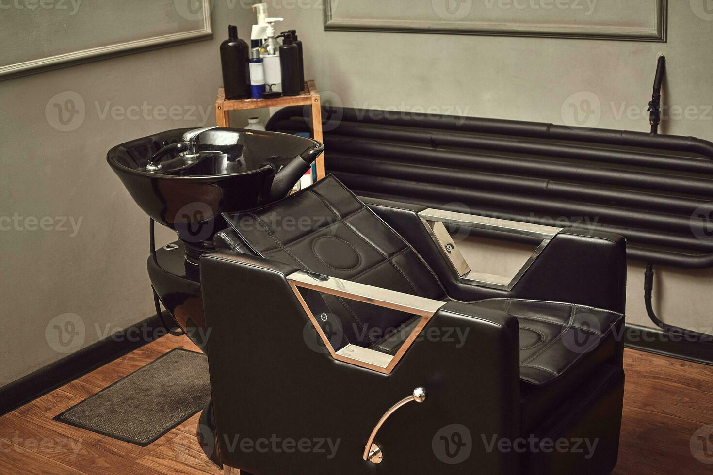 Black leather seat with wash basin in a barbershop interior with towels and shampoo on the side. photo