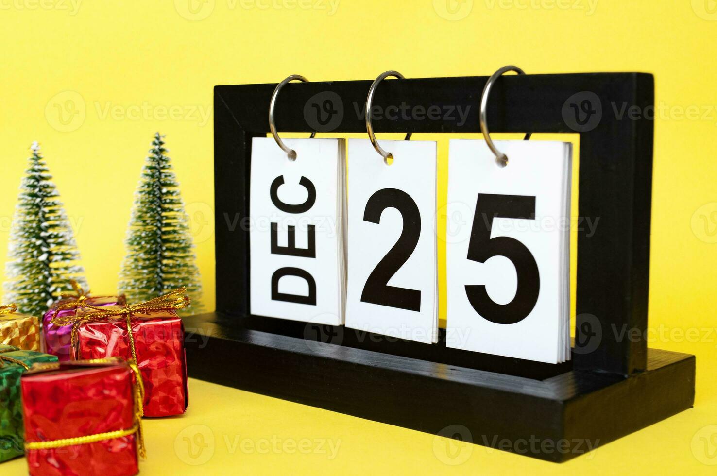 25 December calendar with Christmas tree and presents on yellow background. Christmas concept photo