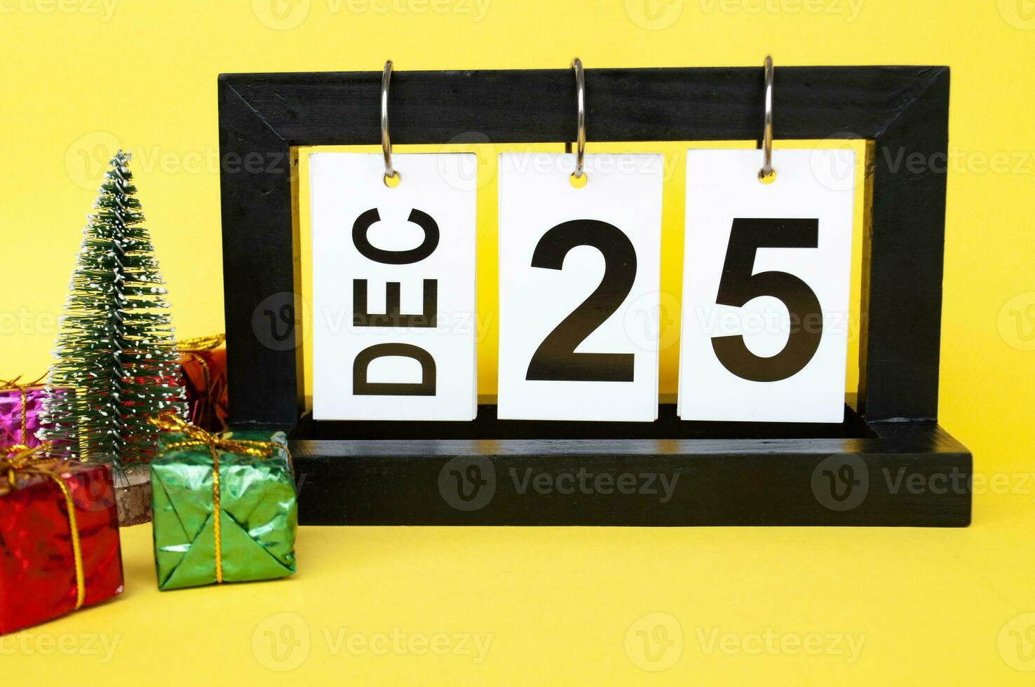 25 December calendar with Christmas tree and presents on yellow background. Christmas concept photo