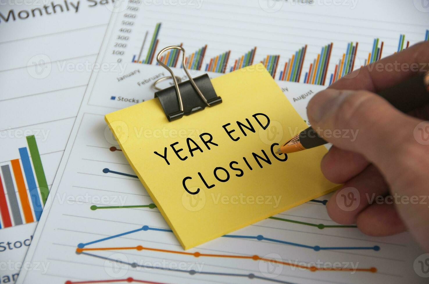 Hand writing Year End Closing text on sticky note with statistic and graph background photo
