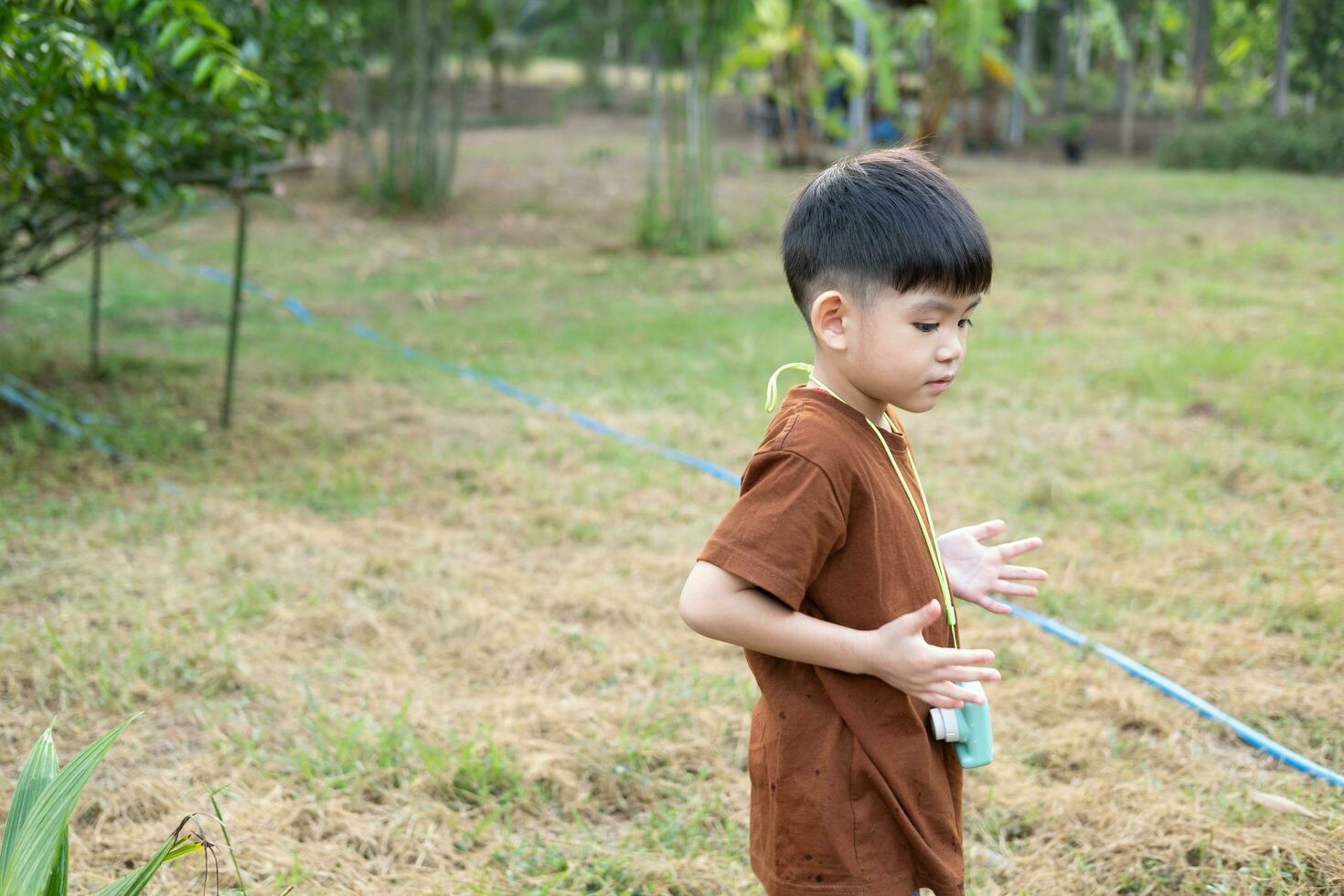 Asian boy standing with arms spread in a relaxed pose at outdoor area photo