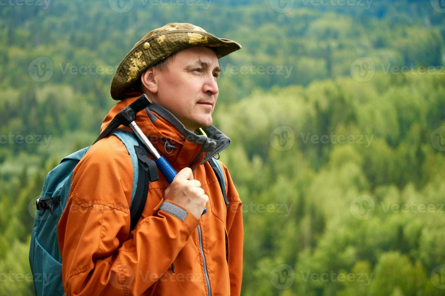 masculino geólogo con un mochila y un geológico martillo en mano en contra el fondo de un enselvado montaña paisaje foto