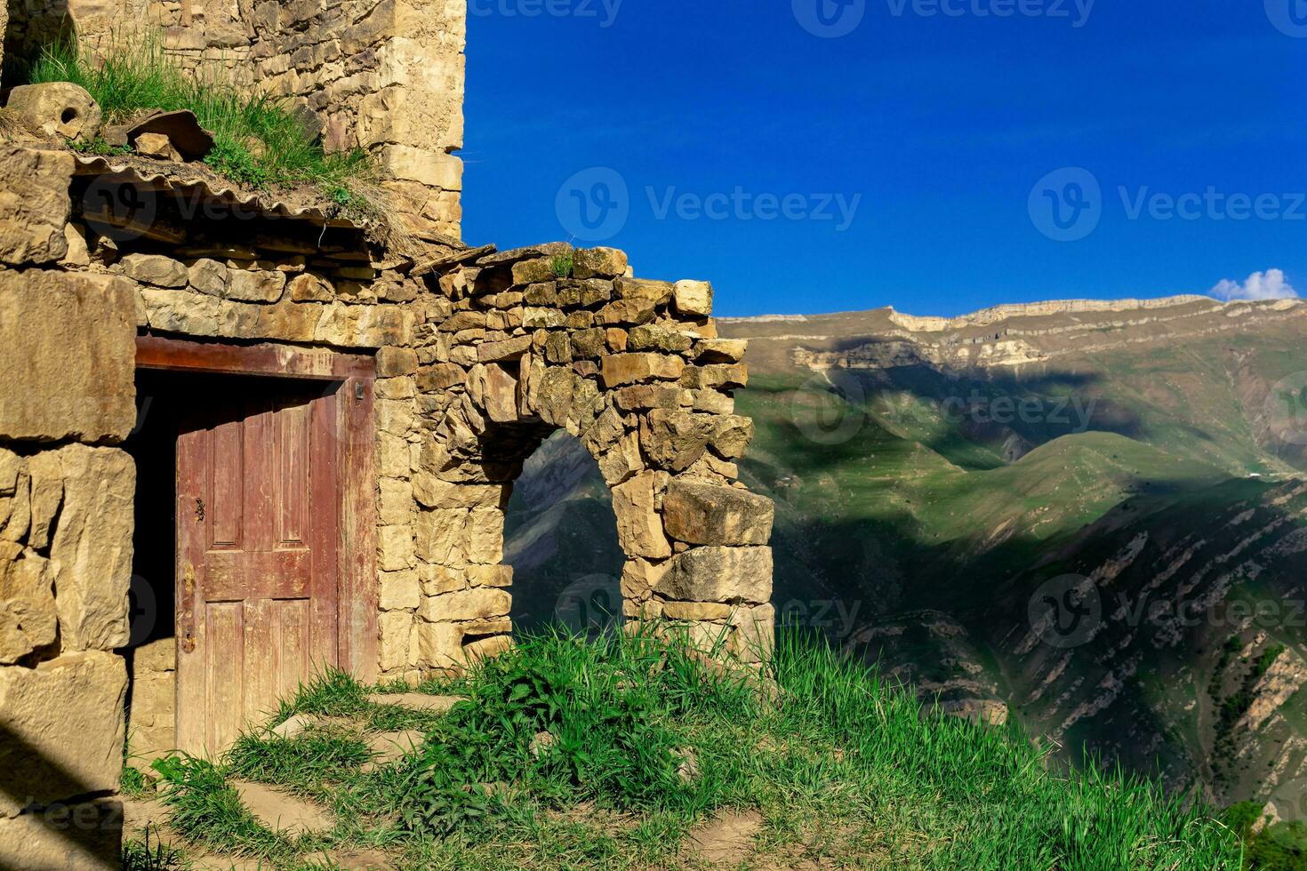 ruins of house in the abandoned village of Gamsutl overlooking the mountains photo