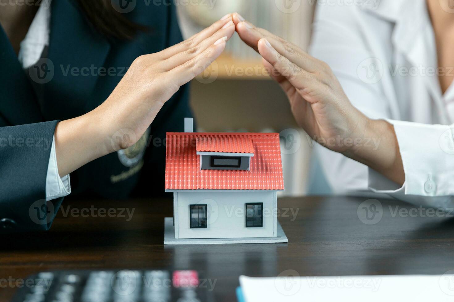 Home protection concept, close up of female hands sheltering modern house, get insurance or loan real estate or property. Approved mortgage application form, concerning mortgage loan offer. photo