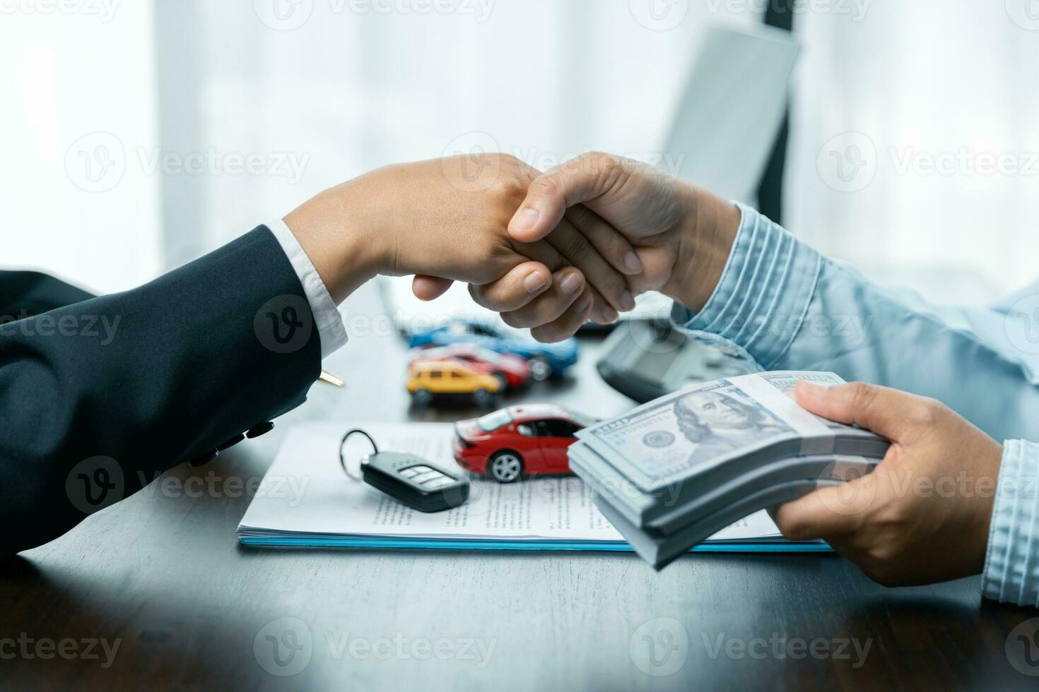 cerca arriba de un apretón de manos a el mesa con juguete coche y llaves. coche comprando concepto. exitoso coche préstamo contrato comprando o de venta nuevo vehículo. foto