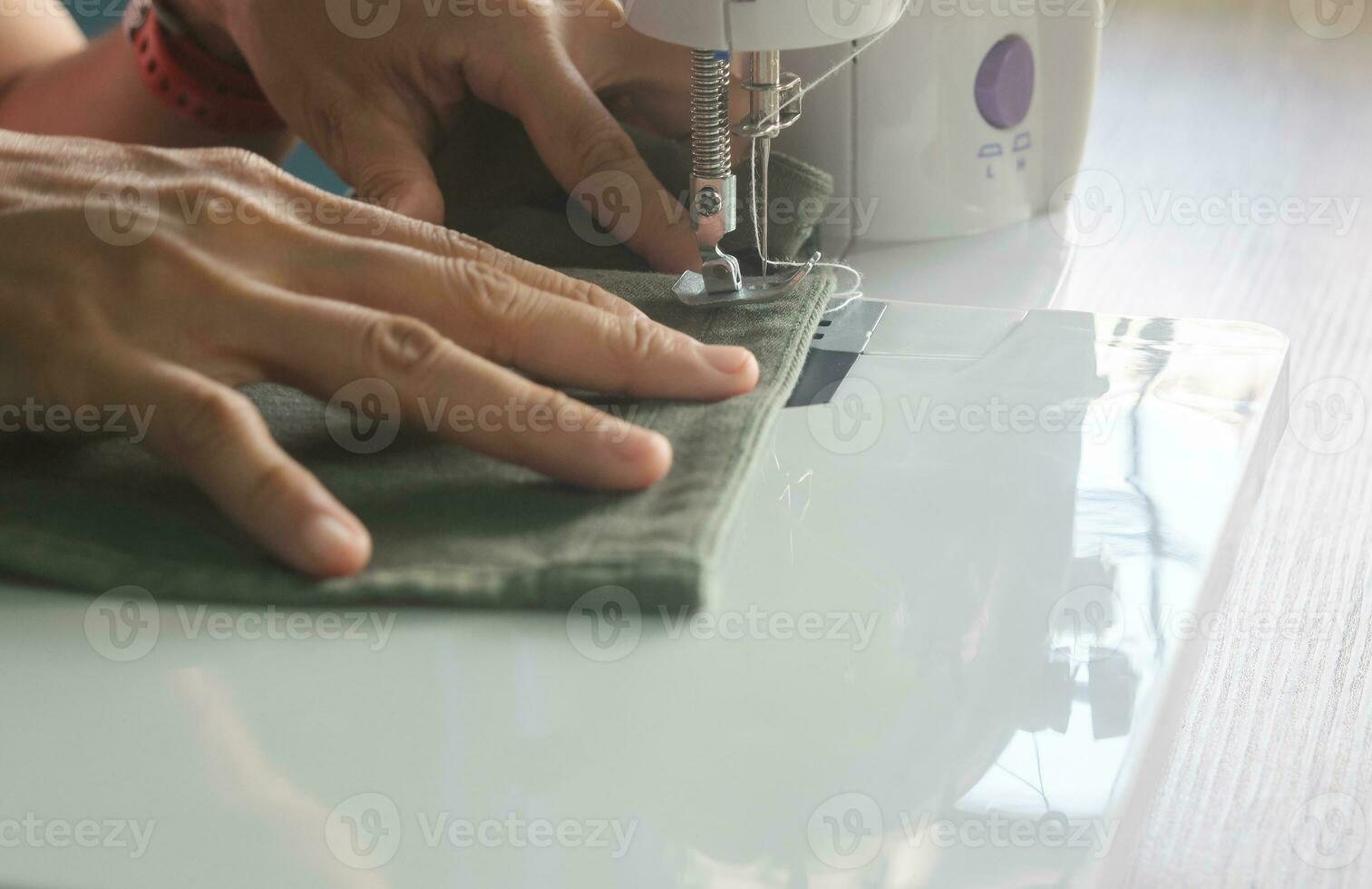 woman mid-adult sitting on chair and repairing clothes using sewing machine working on holiday hobby at home,hand made clothes fasion designer lifestyle concepts photo