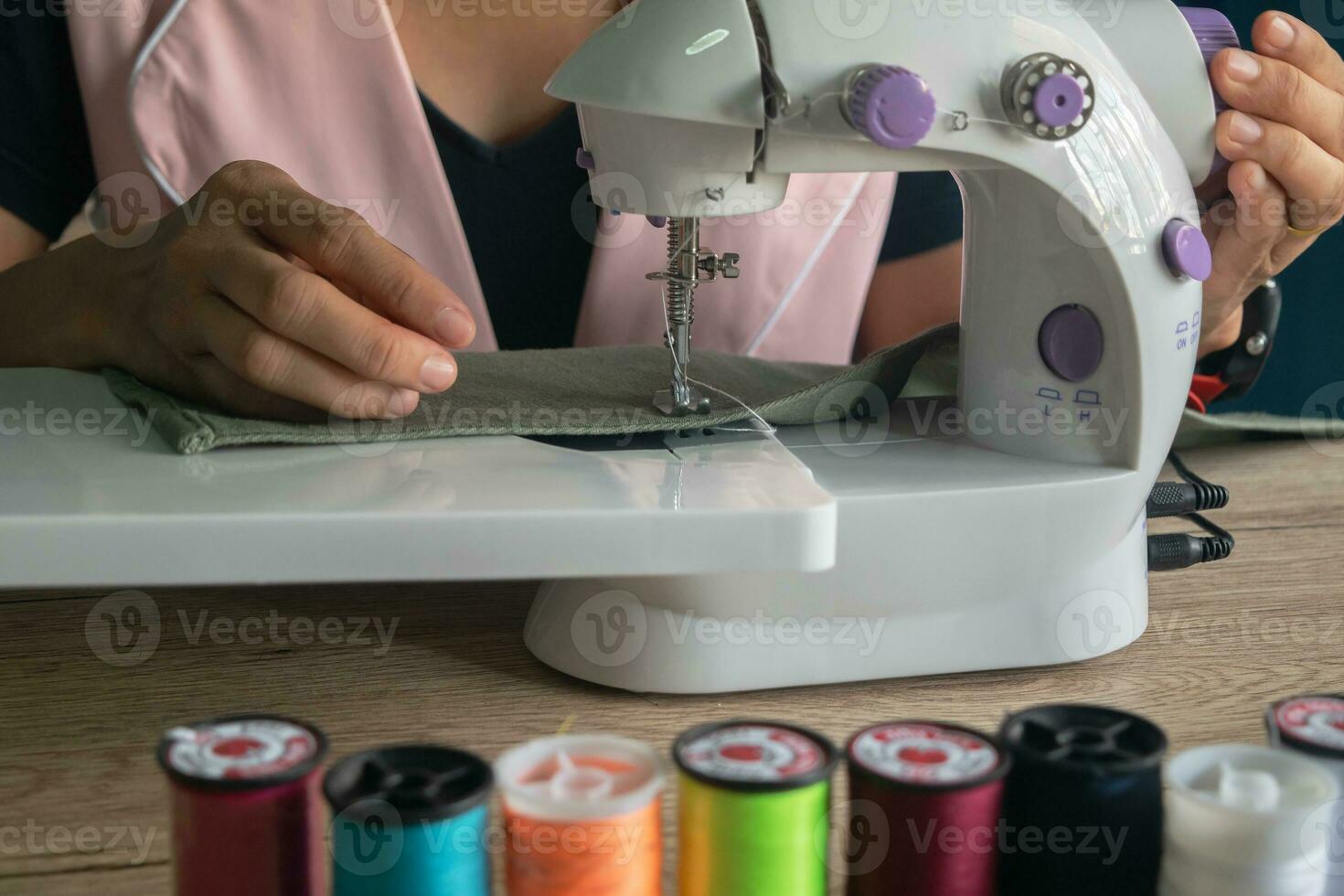 woman mid-adult sitting on chair and repairing clothes using sewing machine working on holiday hobby at home,hand made clothes fasion designer lifestyle concepts photo
