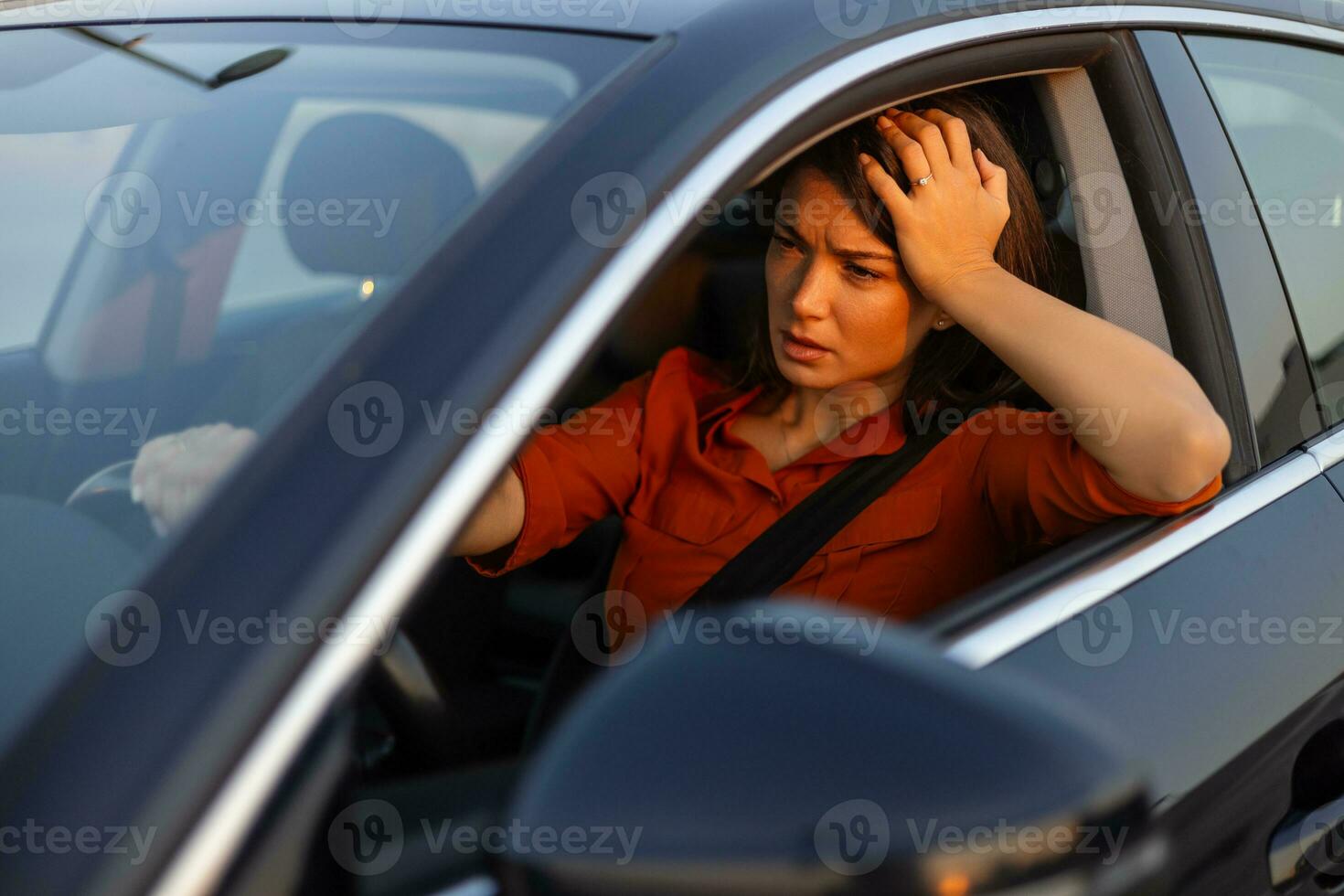 Nervous female driver sits at wheel, has worried expression as afraid to drive car by herself for first time. Frightened woman has car accident on road. People, driving, problems with transport photo