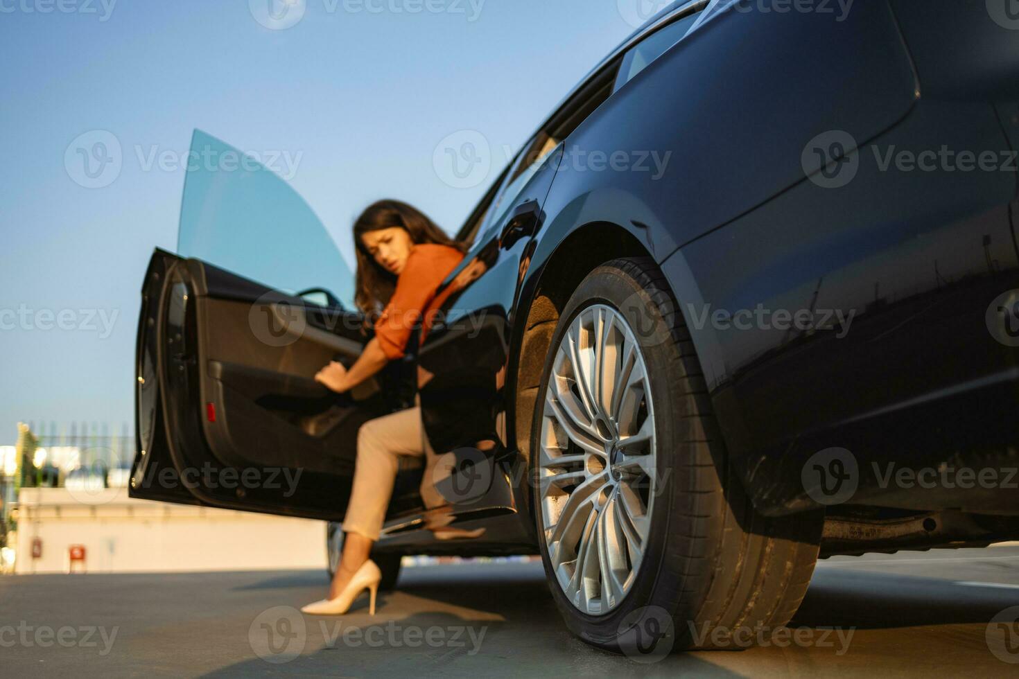 A young woman in the city with a flat tire, frustrated near the broken car. Woman changing a wheel after a car breakdown at the side of the road. This is going to ruin my trip photo