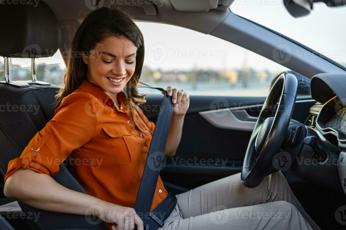 Young woman sitting on car seat and fastening seat belt, car safety concept. Woman fastens a seat belt in the car. Caucasian woman driver fastening car seat belt while sitting behind the wheel car. photo