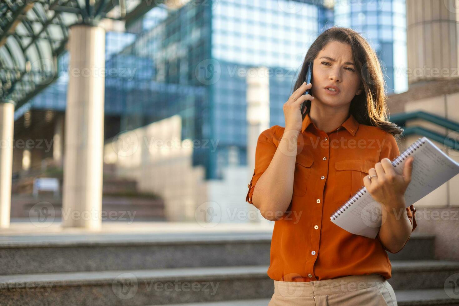 Smiling young business woman wearing suit standing on urban escalator using applications on cell phone, reading news on smartphone, fast connection, checking mobile apps outdoors. photo