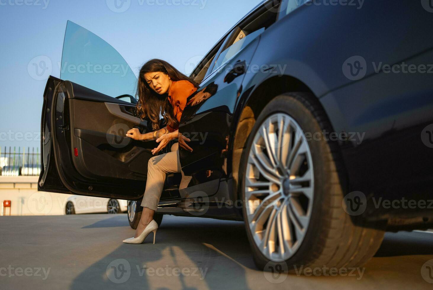 Beautiful woman on a road near her car with punctured car tire. Female driver looking to deflated tire. photo