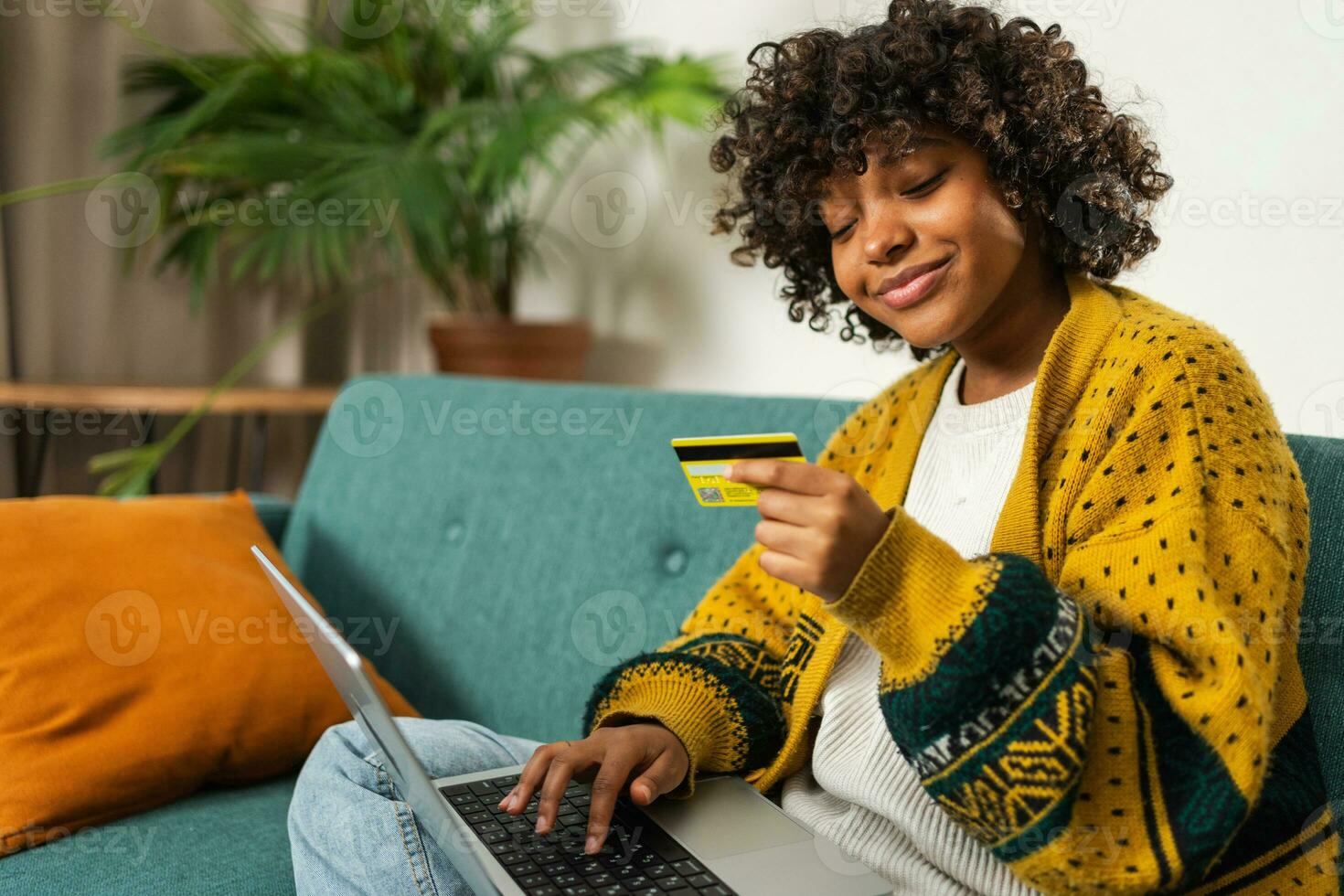 African american woman using laptop shopping online paying with gold credit card. Girl sitting at home buying on Internet enter credit card details. Online shopping ecommerce delivery service. photo