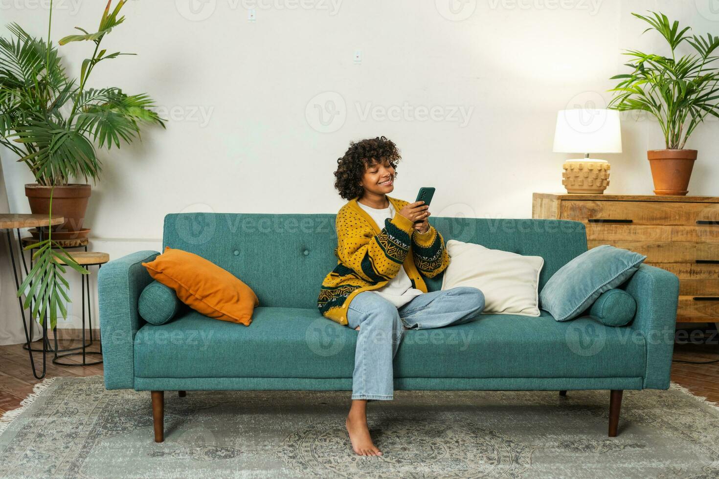 African girl holding smartphone touch screen typing scroll page at home. Woman with cell phone surfing internet using social media apps playing game. Shopping online Internet news cellphone addiction. photo