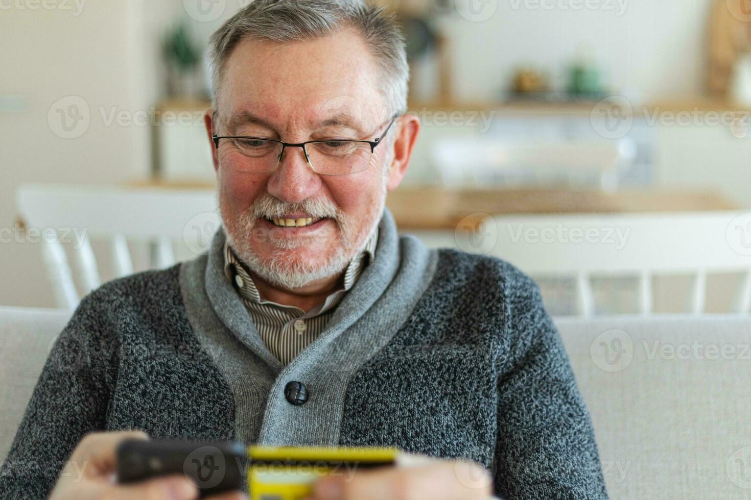 Senior man shopping online holding smartphone paying with credit card Old grandfather buying on Internet enter credit card details. Online shopping delivery service. Older generation modern tech usage photo