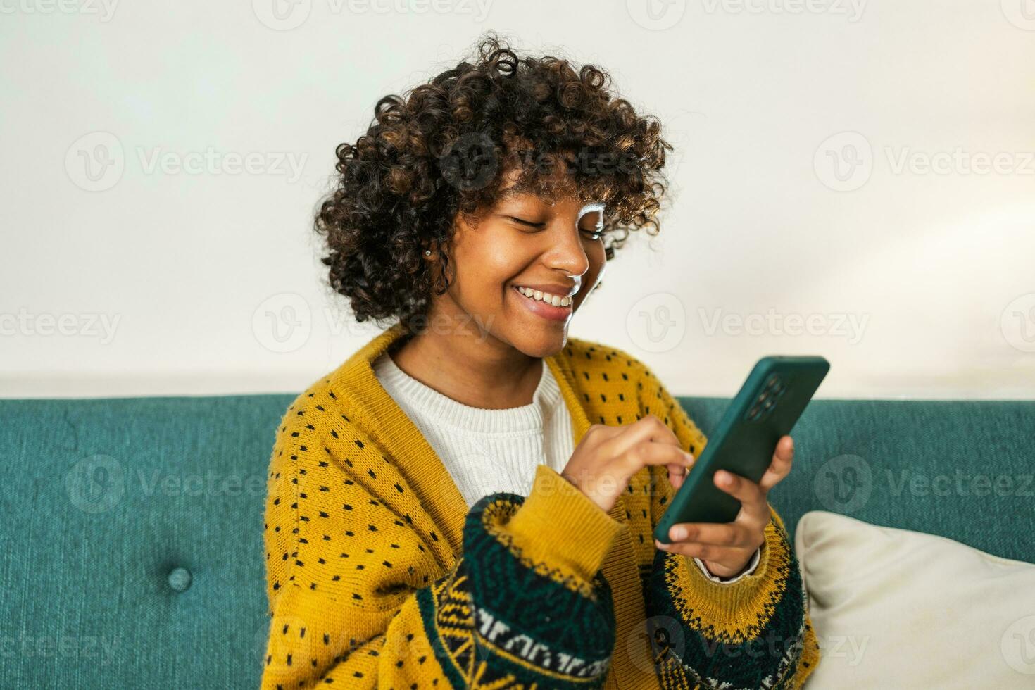African girl holding smartphone touch screen typing scroll page at home. Woman with cell phone surfing internet using social media apps playing game. Shopping online Internet news cellphone addiction. photo