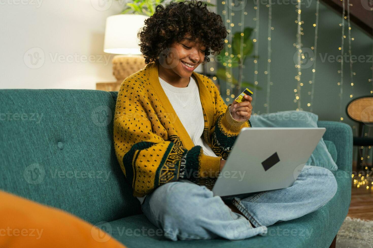 African american woman using laptop shopping online paying with gold credit card. Girl sitting at home buying on Internet enter credit card details. Online shopping ecommerce delivery service. photo