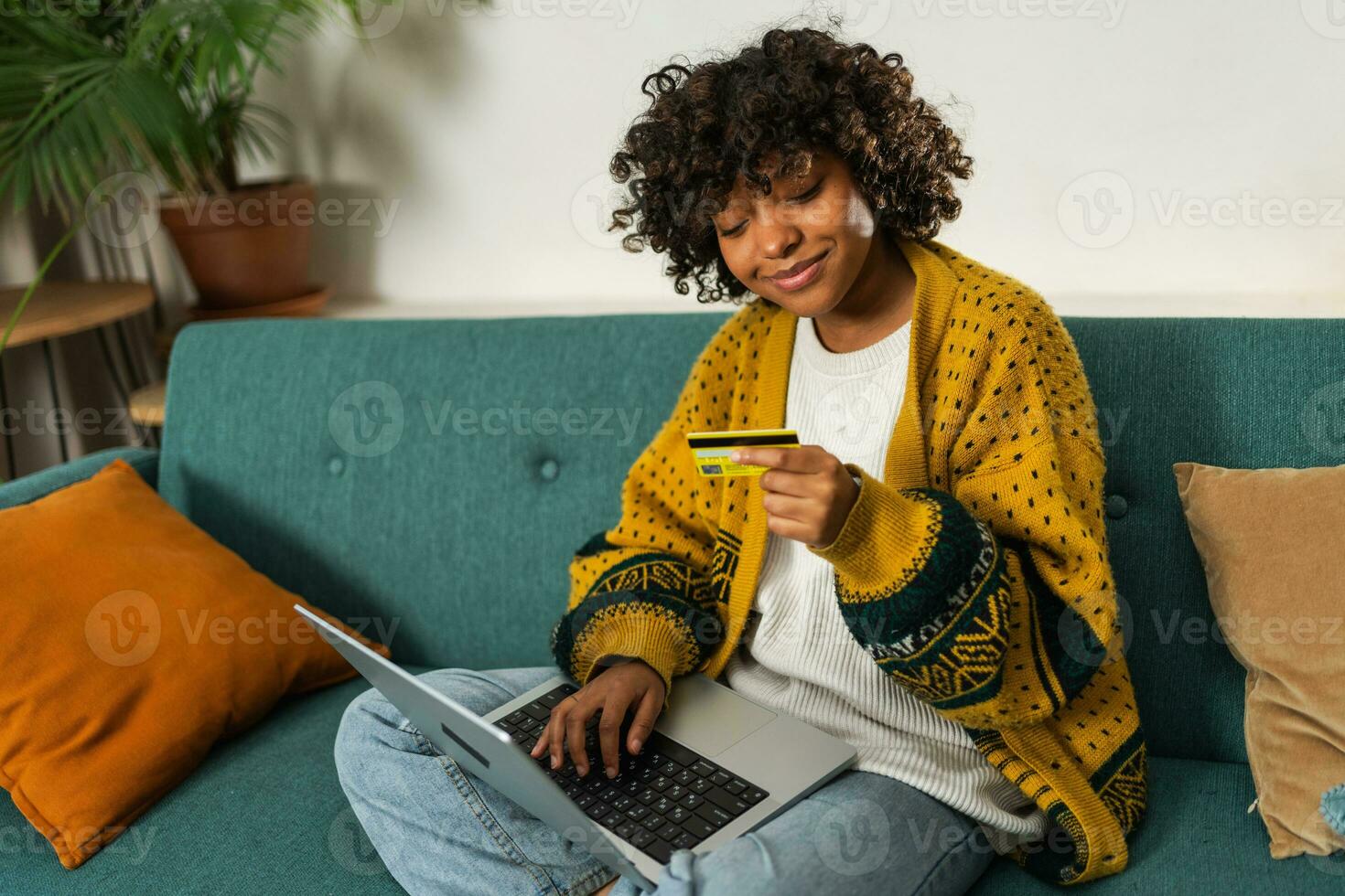 African american woman using laptop shopping online paying with gold credit card. Girl sitting at home buying on Internet enter credit card details. Online shopping ecommerce delivery service. photo