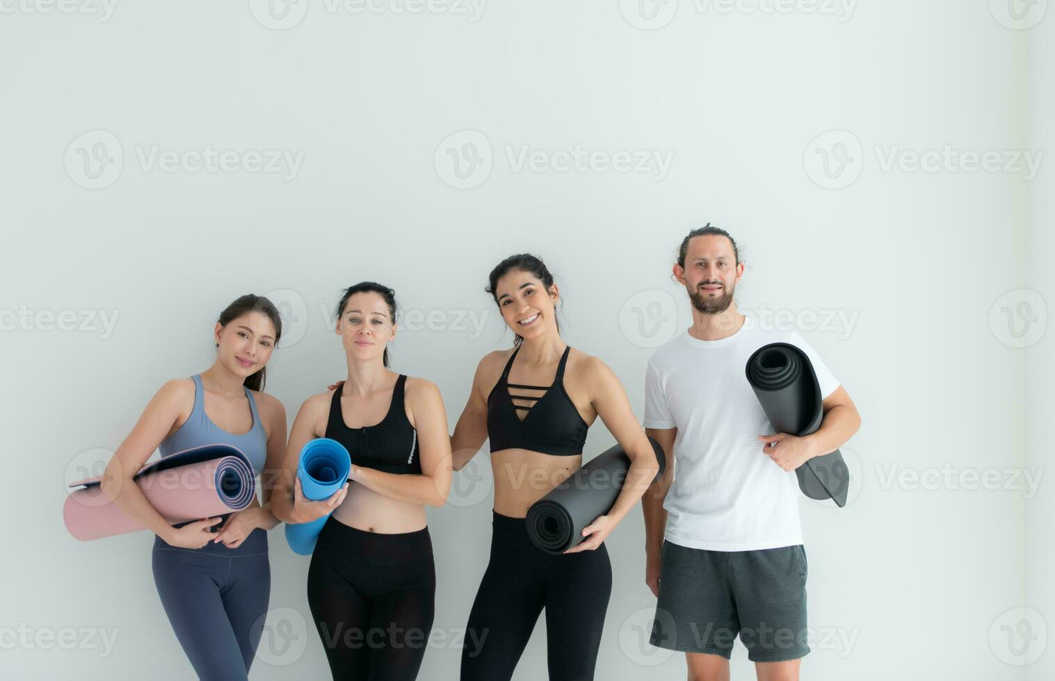 un grupo de hembra y masculino Atletas destacado y charlamos amistosamente en el estudio antes de comenzando con el yoga clase. foto