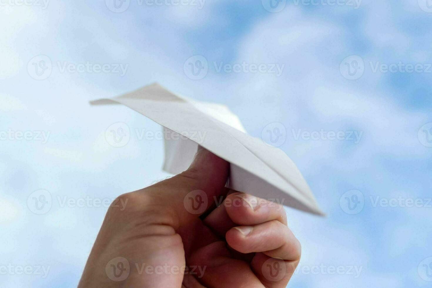a person holding a paper airplane in the air photo