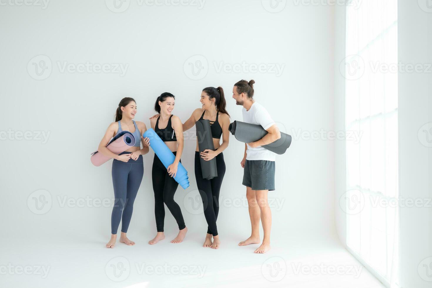 un grupo de hembra y masculino Atletas destacado y charlamos amistosamente en el estudio antes de comenzando con el yoga clase. foto