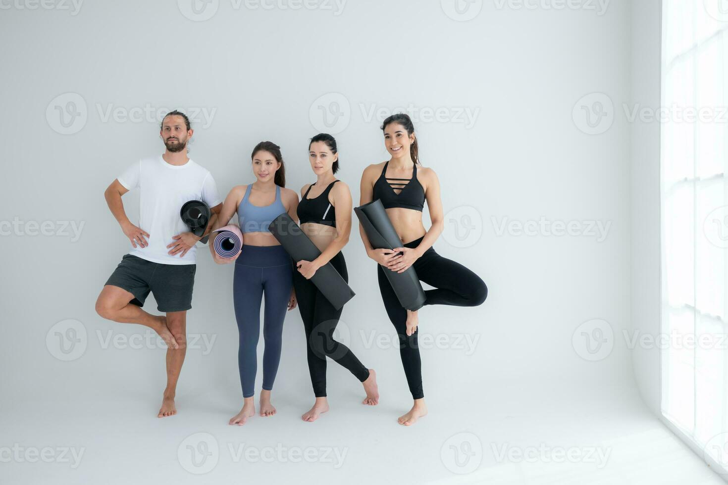 un grupo de hembra y masculino Atletas destacado y charlamos amistosamente en el estudio antes de comenzando con el yoga clase. foto