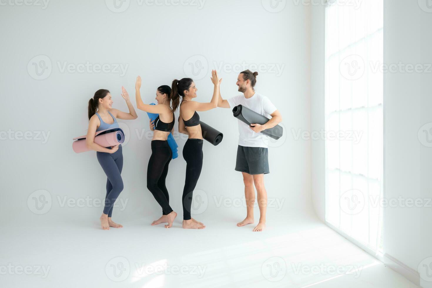 A group of female and male athletes stood and chatted amicably in the studio before beginning with the yoga class. photo