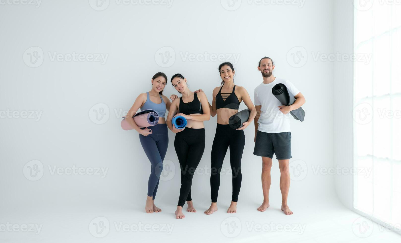 un grupo de hembra y masculino Atletas destacado y charlamos amistosamente en el estudio antes de comenzando con el yoga clase. foto