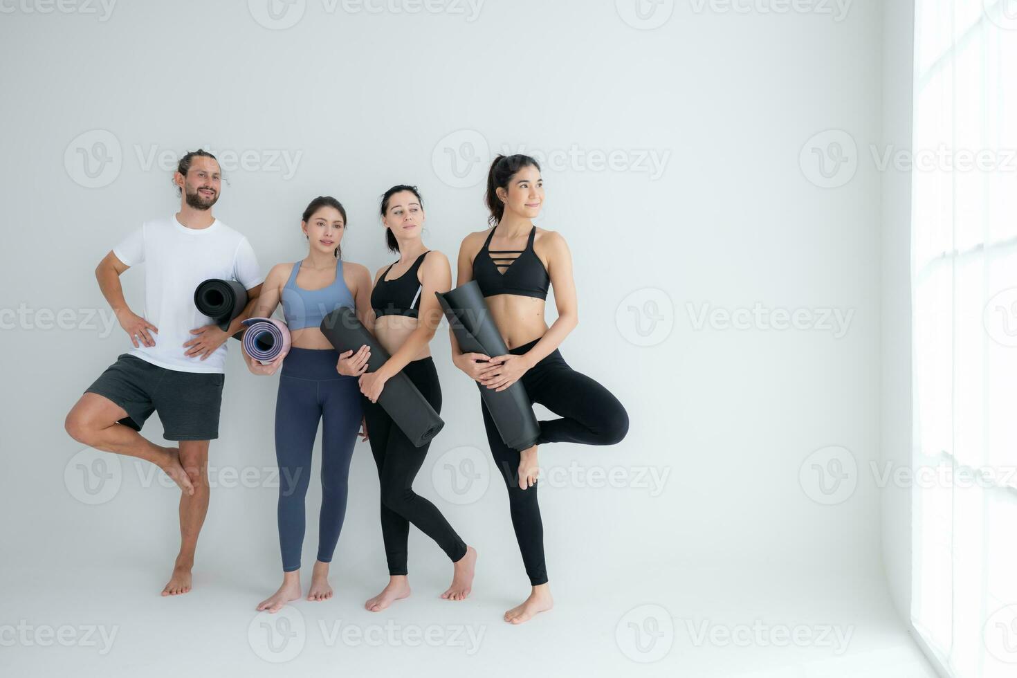 un grupo de hembra y masculino Atletas destacado y charlamos amistosamente en el estudio antes de comenzando con el yoga clase. foto