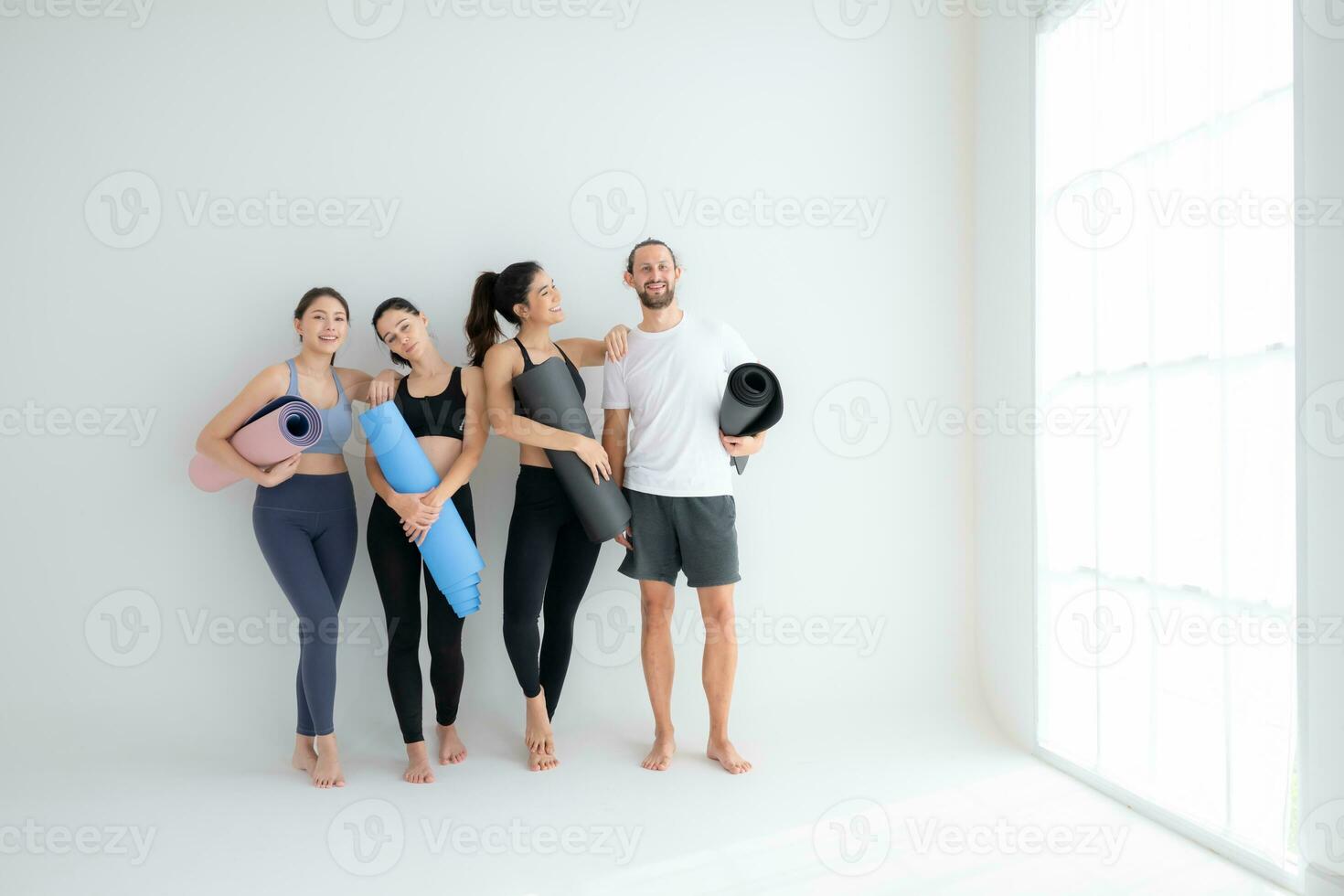 un grupo de hembra y masculino Atletas destacado y charlamos amistosamente en el estudio antes de comenzando con el yoga clase. foto