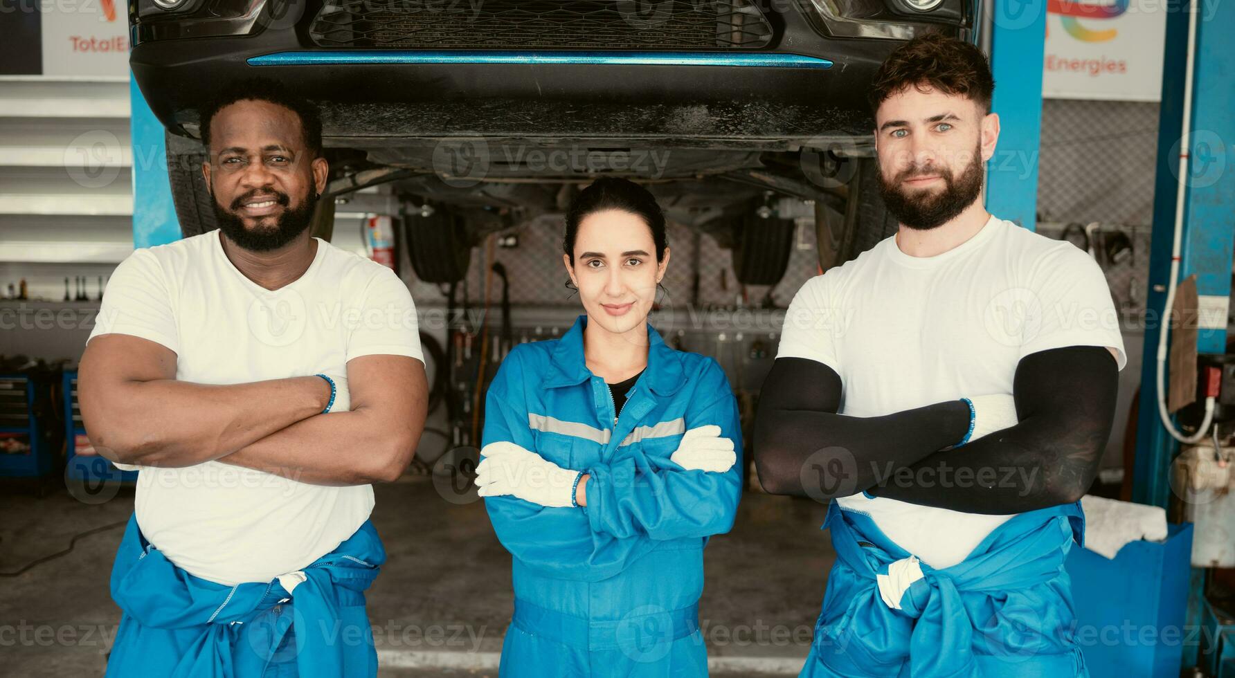 Portrait of smiling mechanics standing in auto repair shop and showing thumbs up photo